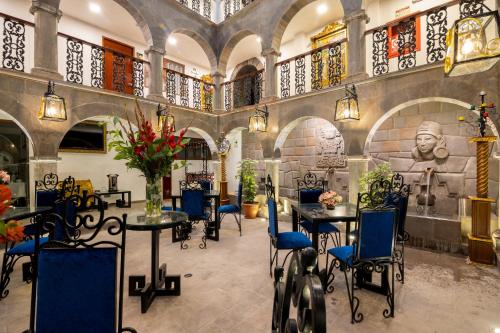 库斯科Hotel Hacienda Cusco Centro Historico的一间带桌椅和雕像的餐厅