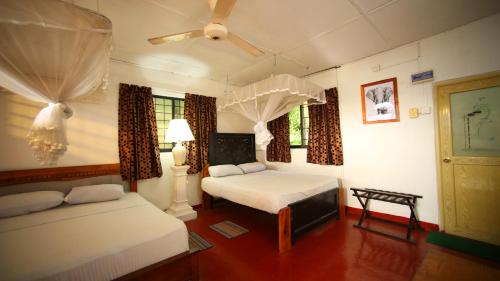 WasgamuwaS and K Safari Village Hotel - Wasgamuwa的一间卧室配有两张床和吊扇