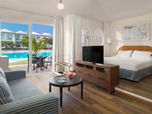 科拉雷侯H10海洋套房酒店的一间卧室设有一张床,客厅设有电视。