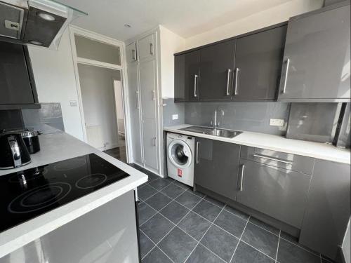 萨顿Bright and spacious 2 bedroom apartment的厨房配有黑色橱柜、洗衣机和烘干机