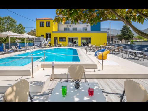 普利瑙港湾Thassian Riviera Hotel的一座带桌椅的游泳池以及一座黄色的建筑