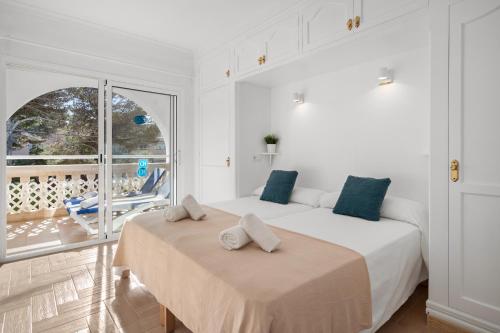 蓬塔普里马Punta Prima Apartments的一间白色卧室,配有两张床和一个阳台