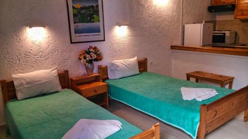阿齐亚佩拉加Fotula Studios的配有绿床单的客房内的两张床