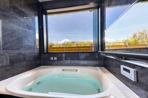 富士河口湖Glamping Cottage Kawaguchiko的一间带大浴缸及大窗户的浴室