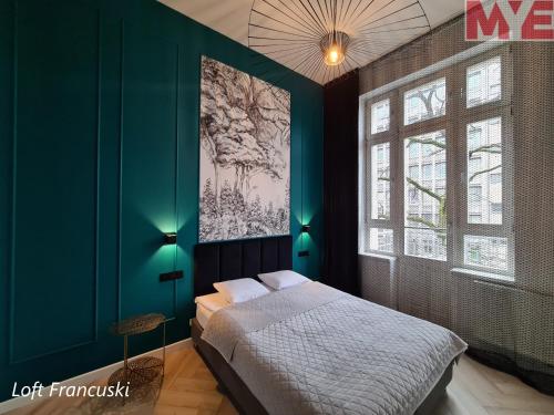 罗兹MYE_Kamienica Sienkiewicza的卧室配有一张床,墙上挂有绘画作品