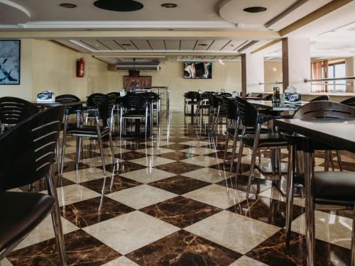 纳祖尔Hotel L'Aéroport的餐厅设有黑色椅子和 ⁇ 板地板