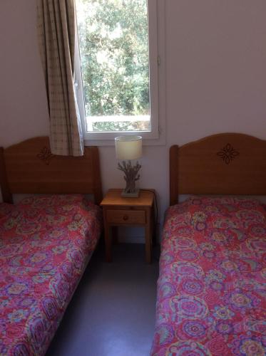 滨海苏拉克Résidence domaine des sables ROUTE 66的一间卧室设有两张床、一个窗口和一张桌子