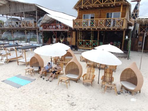 布兰卡滩Hotel Calamari Baru的坐在海滩上桌子上拿着遮阳伞的人