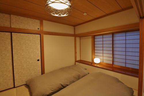 Futoスマートステイ大室山2合目的一间卧室配有一张床、一盏灯和窗户