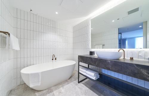 阿德莱德阿德莱德铂尔曼酒店的白色的浴室设有浴缸和水槽。