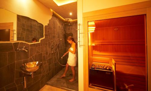 蒙塔尼亚Engadiner Apartments & Wines的站在带淋浴的浴室中的女人