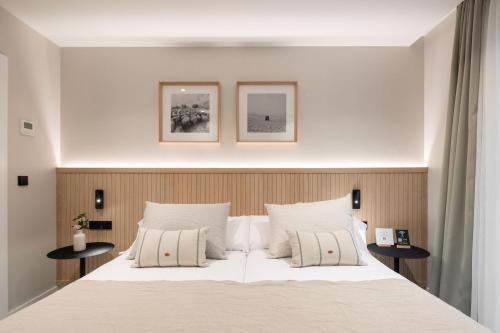 维多利亚-加斯特伊兹NIREA HOTEL的卧室配有一张带两张桌子的大型白色床