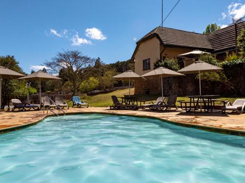皮尔格林斯雷斯特Crystal Springs Mountain Lodge的一个带椅子和遮阳伞的游泳池以及一座房子