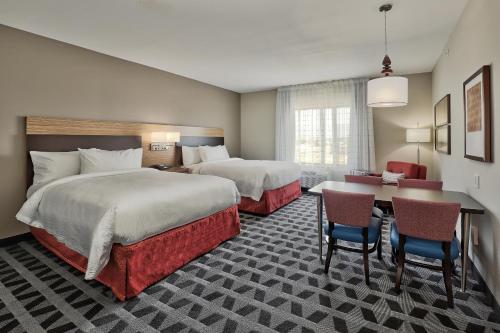 阿尔伯克基TownePlace Suites by Marriott Albuquerque Old Town的酒店客房带两张床和一张桌子以及椅子。
