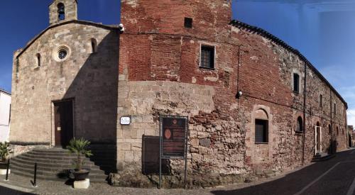 奥里斯塔诺Monastero Santa Chiara Guest House的一座古老的砖砌建筑,设有钟楼
