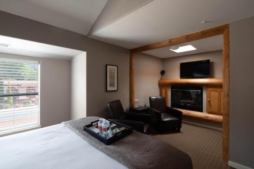塞多纳Inn Above Oak Creek Sedona的酒店客房配有一张床、两把椅子和一台电视