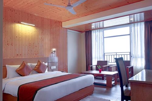 甘托克Treenz Hotel的配有一张床、一张书桌和一扇窗户的酒店客房