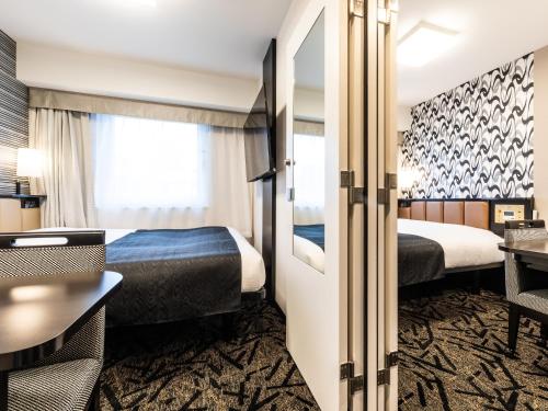 大阪APA Hotel Namba Shinsaibashi Higashi的酒店客房配有两张床和一张书桌