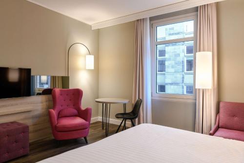 不莱梅不来梅丽笙布鲁酒店的酒店客房配有一张床、两把椅子和一张桌子