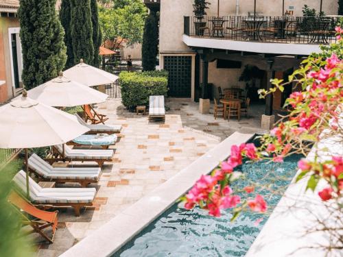 危地马拉安地瓜Villa Santa Inés的一个带椅子和遮阳伞的庭院和一个游泳池