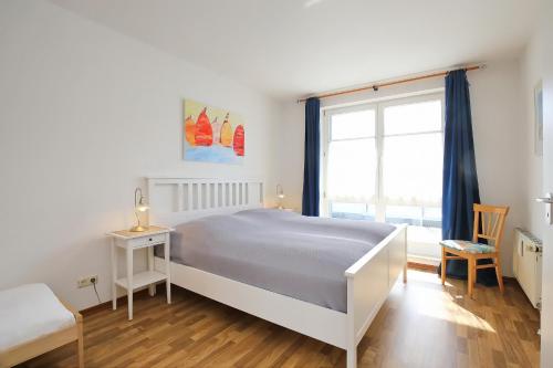 博尔滕哈根Dünenblick Wohnung 48的白色的卧室设有床和窗户