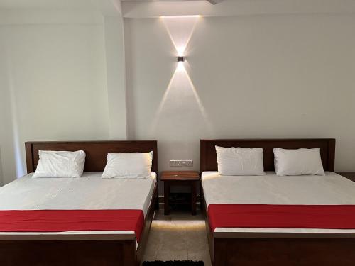 阿努拉德普勒Nugasewana Guest的墙上有灯的房间里设有两张床