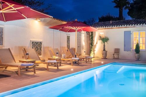 圣马丹德雷La Baronnie Hôtel & Spa - Teritoria的房屋旁的游泳池配有椅子和遮阳伞