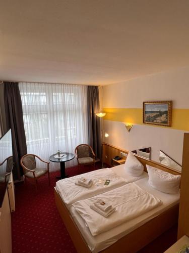 奥斯赛拜-屈隆斯博恩Hotel Poseidon的酒店客房配有一张床铺和一张桌子。
