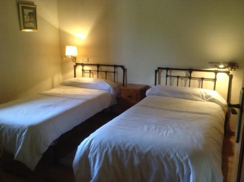 Triongo宝藏度假屋的配有白色床单的客房内的两张床