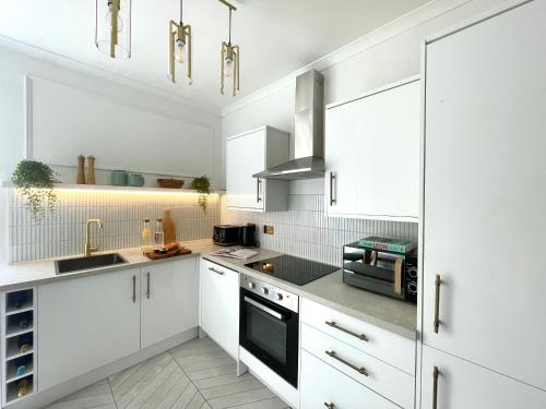 珀斯Stylish & Chic Central Apartment with Hot Tub的白色的厨房配有白色橱柜和电器