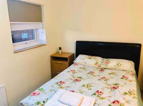卢顿Private room 4-5 minutes drive to Luton Airport的一间卧室配有一张带花卉床罩的床和窗户。