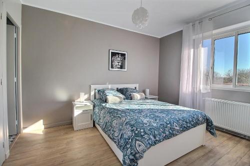 布尔日ÉPIPAPU Appartement 57 M2 - Parking privé - Loggia -的一间卧室配有一张带蓝色床罩的床和窗户。