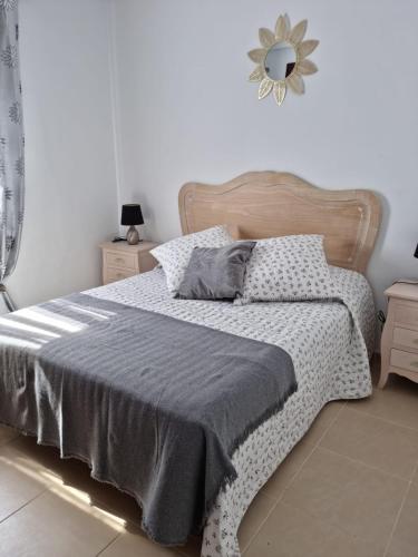 克萨达城AGRADABLE ADOSADO CON PISCINA的一间卧室配有一张带灰色毯子和镜子的床