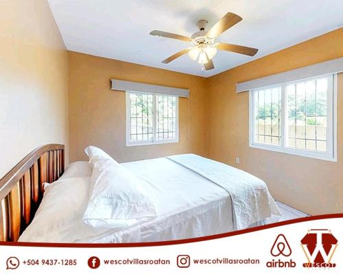 罗阿坦Wescot Villas Comfort的一间卧室配有一张带吊扇的床