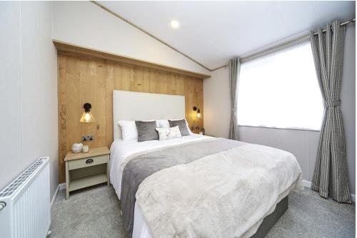佩恩顿Luxury Lodge - Hoburne Devon Bay的一间卧室设有一张大床和一个窗户。