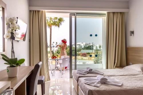 阿依纳帕Bellini Hotel的酒店客房设有两张床,阳台上配有一张桌子和一张女人桌。