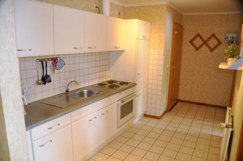 费马恩Ferienwohnung 7, OG, Hof zur Sonnenseite Fehmarn的厨房配有白色橱柜和水槽