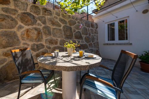 杜布罗夫尼克Apartment Ruzica的一个带石墙的庭院里的桌椅