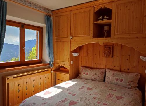 Lagolo di CalavinoChalet nel bosco con lago e panorama mozzafiato的一间卧室设有一张床和一个大窗户