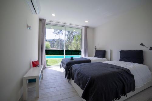卡米尼亚Villa Rencanto – um espaço com a sua assinatura的带大窗户的客房内的两张床