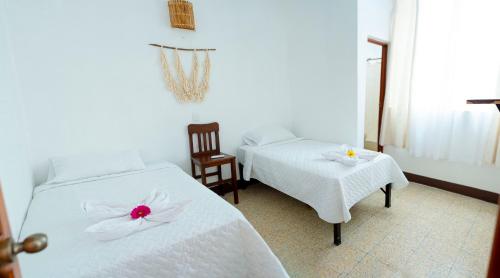 弗洛勒斯Casa Ramona的一间卧室配有两张床,提供白色的床单和鲜花