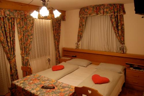 圣维吉利奥赞致亚纳酒店的一间卧室配有两张床和一张带红色枕头的桌子。