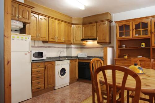 贝纳斯克Apartamentos Los Tilos的厨房配有木制橱柜、桌子和白色冰箱。