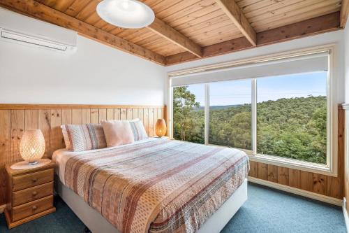 洛恩布什房子村舍和生态旅馆的一间卧室设有一张床和一个大窗户