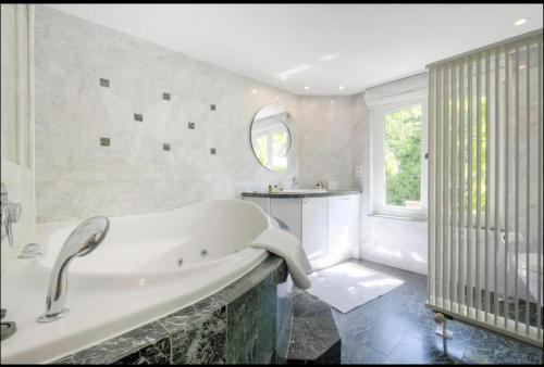 布鲁塞尔La Calamande En Ville的白色的浴室设有浴缸和窗户。