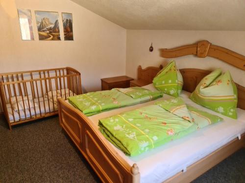 圣兰布雷希特Schöne Ferienwohnung im Naturpark Grebenzen的一间卧室配有一张带绿床单的床和一张婴儿床。