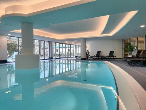 波茨坦多林特三索斯柏林/波茨坦酒店的酒店大堂的大型游泳池,带泳池导览器