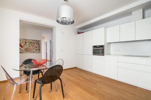博洛尼亚Santo Stefano Design Apartment by Wonderful Italy的厨房配有白色橱柜和玻璃桌椅