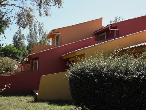 博尔戈Holiday Home Cala Bianca-1 by Interhome的一座红色和黄色的房子,前面有灌木丛