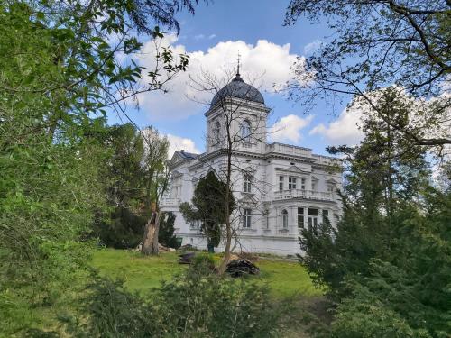 弗罗茨瓦夫Stara Biblioteka的一座白色的建筑,在田野上设有钟楼